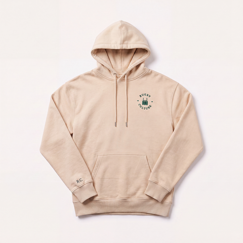 A light beige pullover hoodie with a drawstring hood, kangaroo pocket, and a small green circular graphic on the left chest reading 'Rugby Culture'. A small 'RC' logo is printed on the left sleeve.