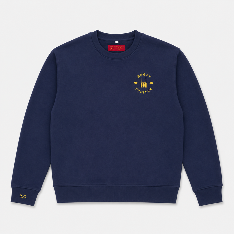 A navy blue crewneck sweatshirt with a yellow 'Rugby Culture' graphic on the left chest and a small yellow 'R.C' logo on the right cuff, displayed flat against a light gray background.