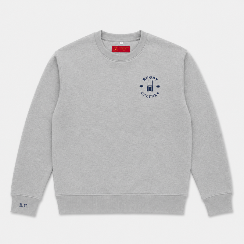 A light gray crewneck sweatshirt with a navy blue 'RUGBY CULTURE' graphic on the left chest and a small 'R.C.