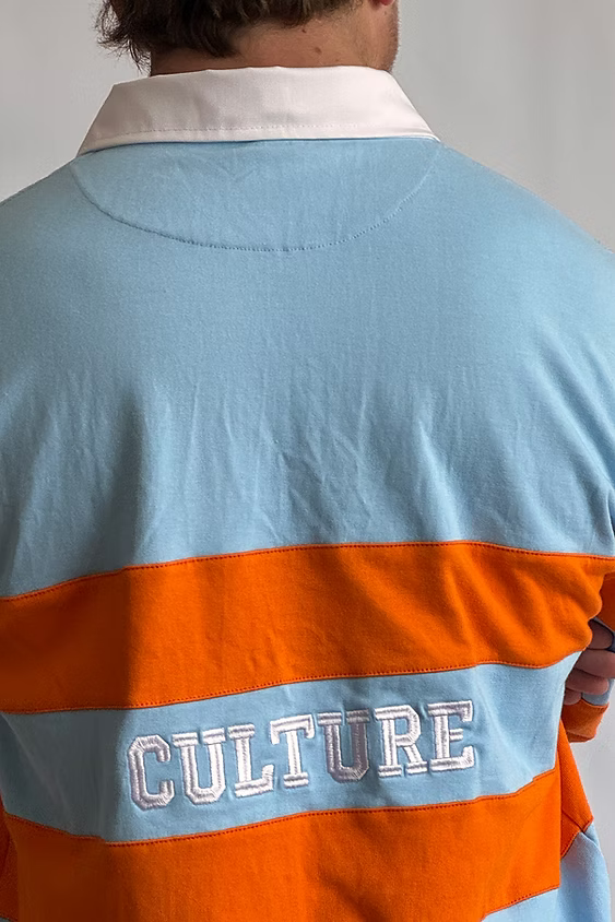 Close-up of 'CULTURE' across the back of the Rugby Culture Sky Blue & Orange Rugby Polo