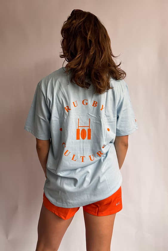Rugby Culture Baby Blue Back Print T-Shirt worn by a female model, back view showing the back print