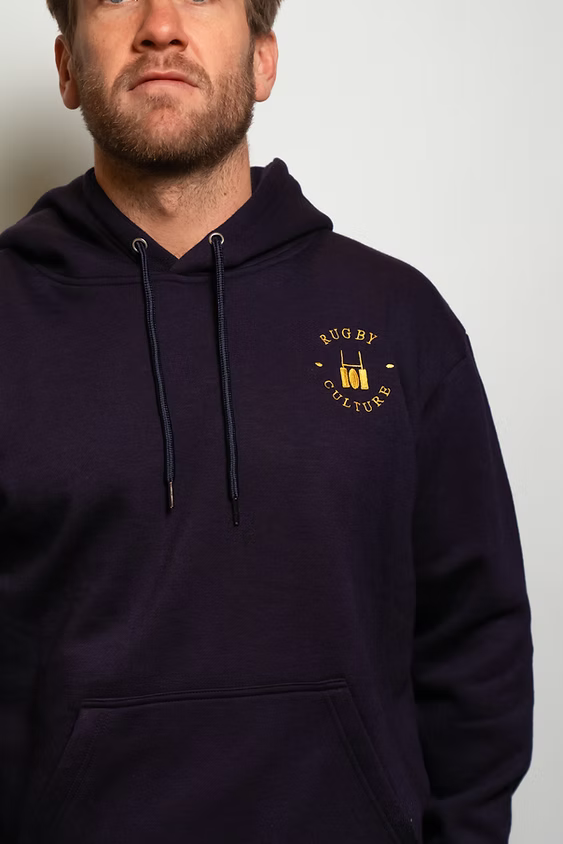 Rugby Culture Navy Blue Hoodie worn, close-up of the chest emblem