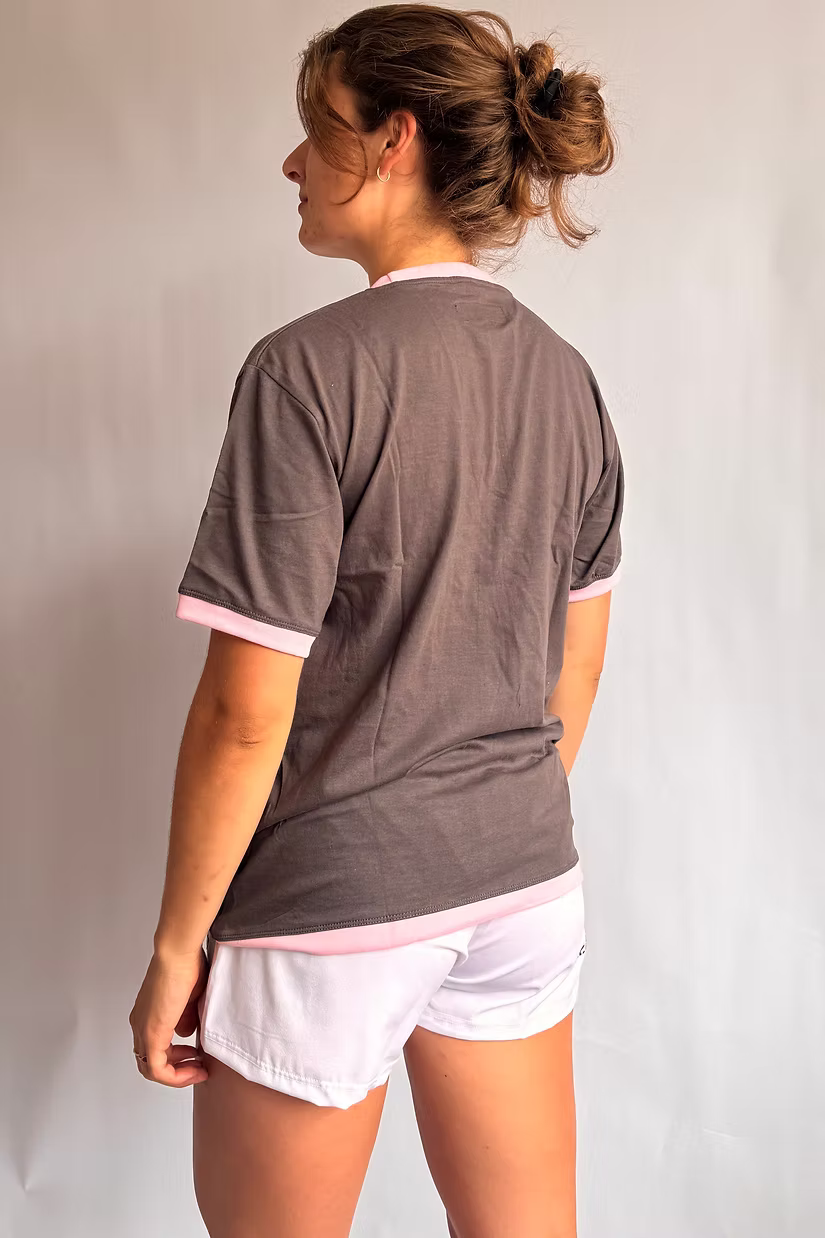 Rugby Culture Deep Grey & Pink Logo T-Shirt worn by a female model, back view, with white shorts