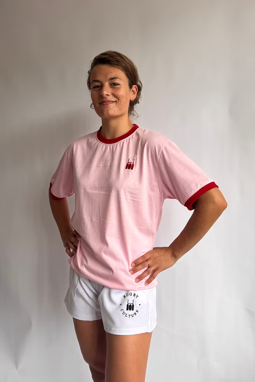 Rugby Culture Pink & Red Logo T-Shirt worn by a female model, front view, hands on hips