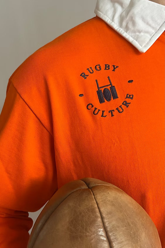 Close-up of the circular Rugby Culture emblem on the Kids Netherlands Rugby Polo