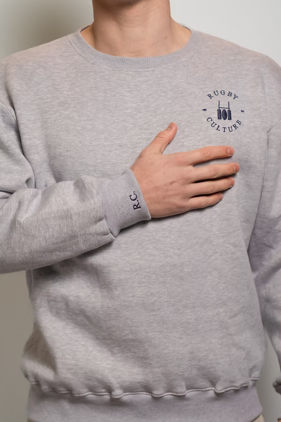 Rugby Culture Grey Sweatshirt worn, close-up with hand on chest