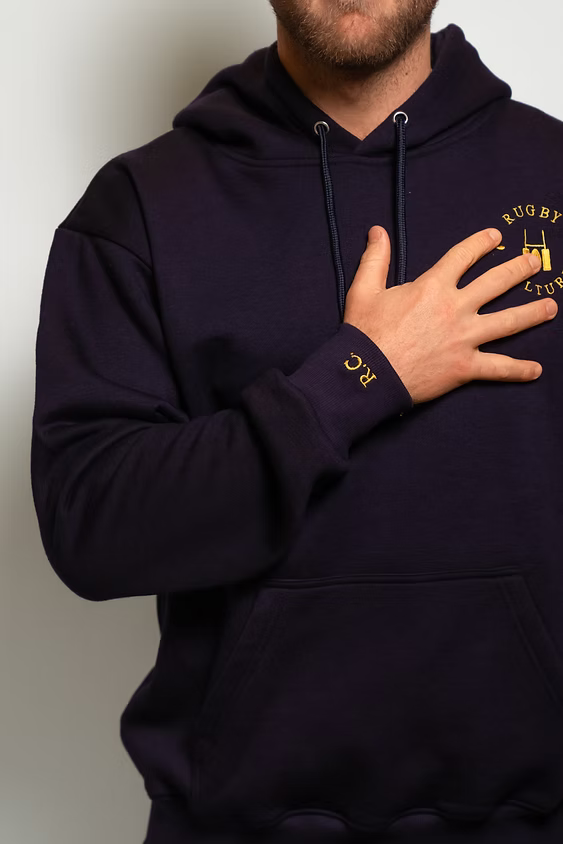 Rugby Culture Navy Blue Hoodie worn, close-up with hand on chest