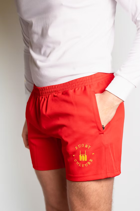 Rugby Culture Red Scrum Shorts worn with a white top, front view, hand in pocket