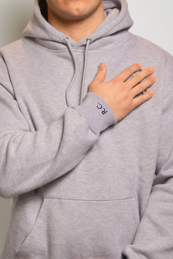 Rugby Culture Grey Hoodie worn, close-up with hand on chest