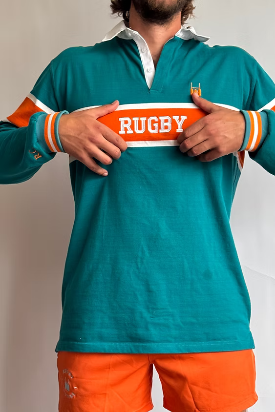 Male model adjusting the collar of the Rugby Culture Teal & Orange Rugby Polo