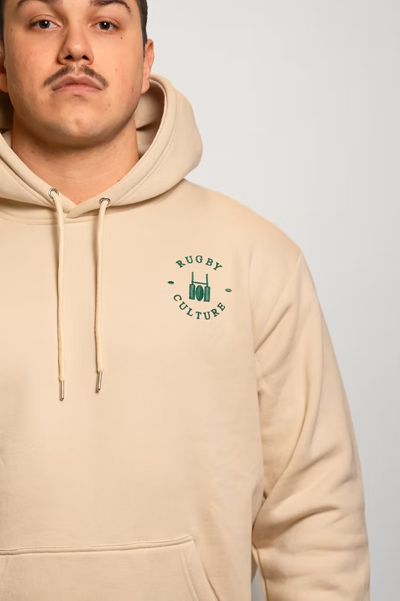 Rugby Culture Beige Hoodie worn, close-up of the chest emblem