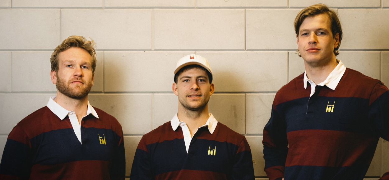Three men wearing matching striped rugby polo's against a tiled wall.